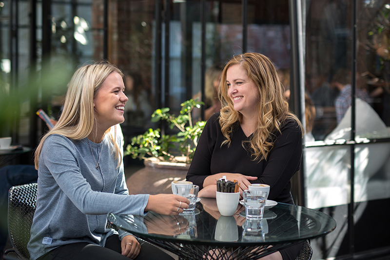 Keystone alumni Simone Sharp sits at a cafe table talking a student